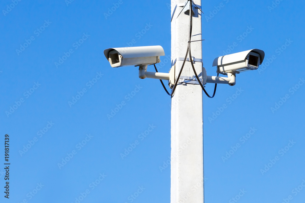 two CCTV cameras mounted on a pole against a blue sky two CCTV cameras mounted on a pole against a blue sky