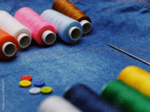 Background jeans fabric, thread, needles with threads, colorful background. Concept sewing business, business fabrics, sewing workshop. Place for text