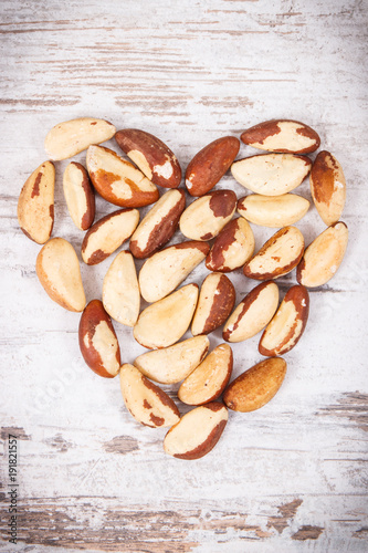 Heap of brazil nuts in shape of heart, healthy food containing natural minerals