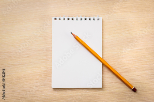 Blank notebook and pencil on wooden background