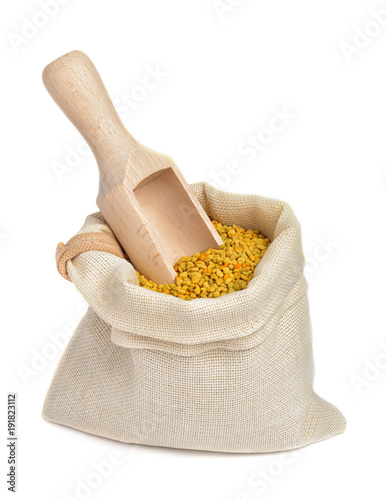 Flower bee pollen in a bag with a wooden scoop isolated on a white background. A natural source of vitamins and minerals. Beekeeping products. Apitherapy.