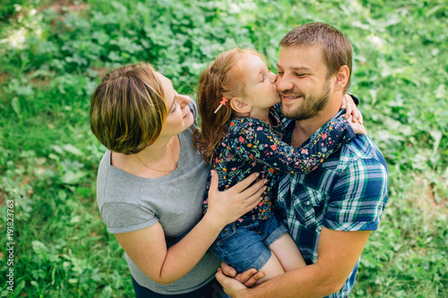 Cute young happy family having fun in the park. Little girl with parents outdoors. Mother father and daughter.