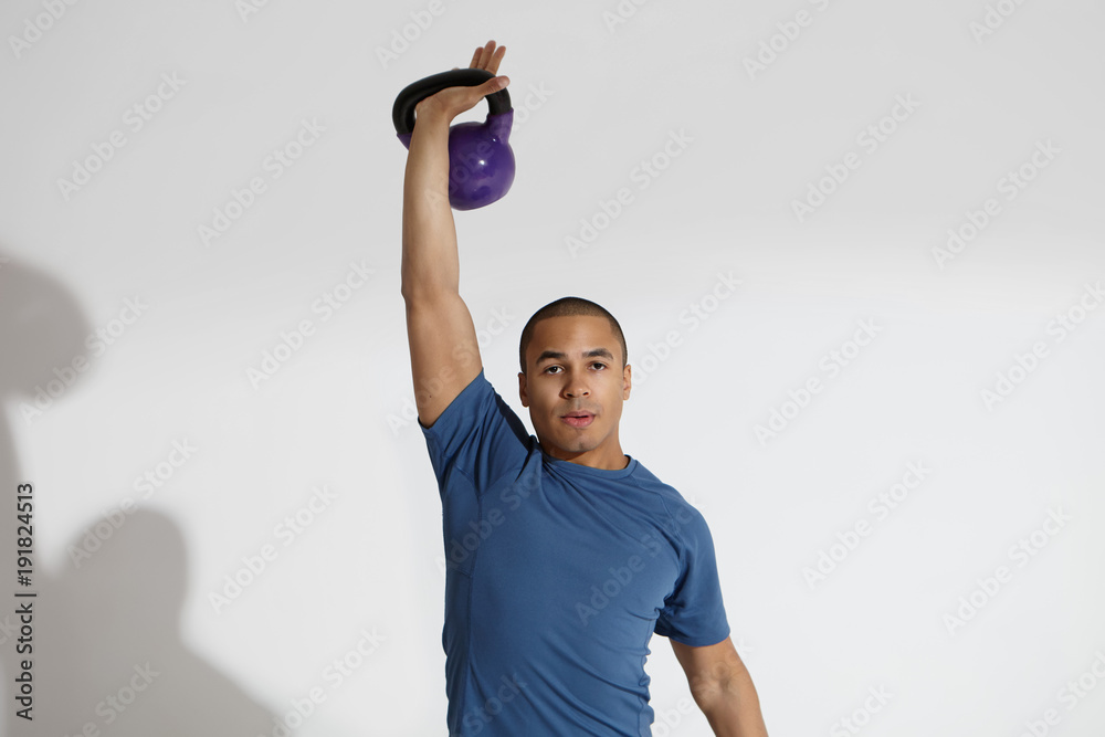 Cropped studio shot of strong young Afro American male athlete wearing blue t-shirt training in gym using heavy weight, lifting dumbbell above his head. Fitness, powerlifting and bodybuilding Cropped studio shot of strong young Afro American male athlete wearing blue t-shirt training in gym using heavy weight, lifting dumbbell above his head. Fitness, powerlifting and bodybuilding