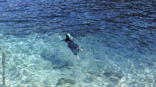 A Muslim woman is swimming in the sea.