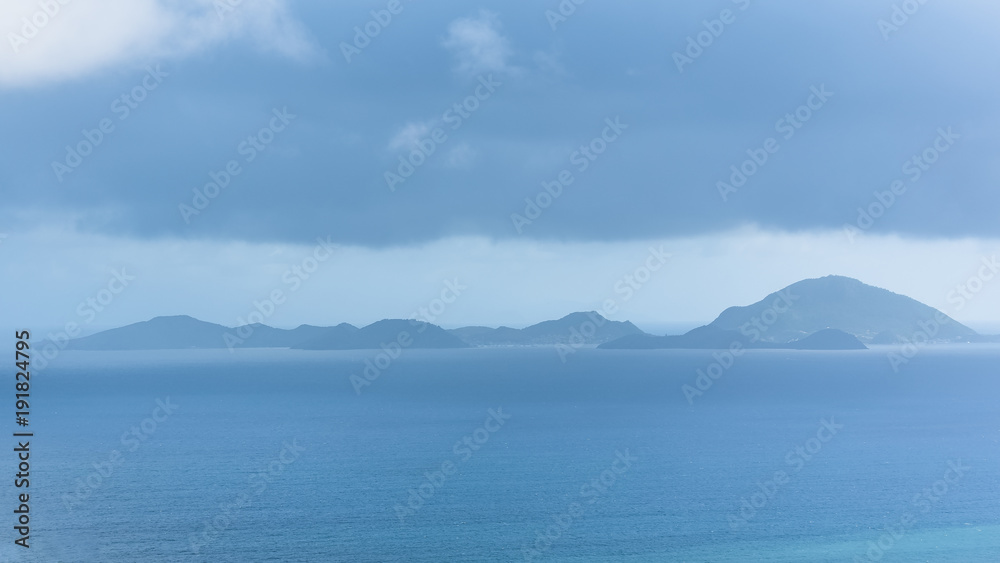 Les Saintes islands in Guadeloupe, panorama between sea and sky, view from Basse Terre, rainy in background 
