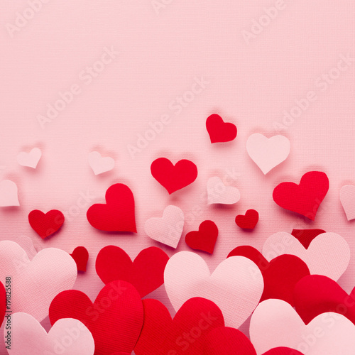 Valentine day background of fly paper red and pink hearts on pink color backdrop. Copy space.