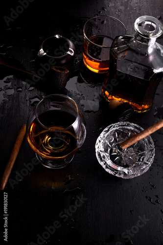 Glass of whiskey with smoking cigar.
