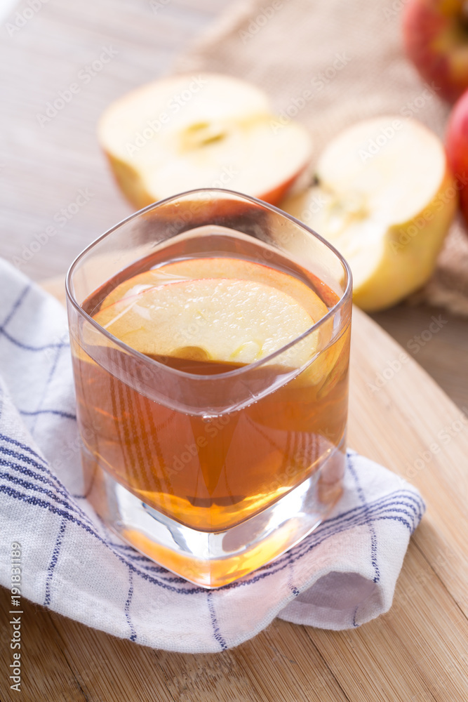 Apple cider vinegar in a glass cup, with apples on table. Apple cider vinegar in a glass cup, with apples on table.