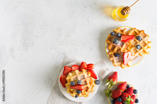 Plate with waffles with strawberries and blueberries and cup of tea