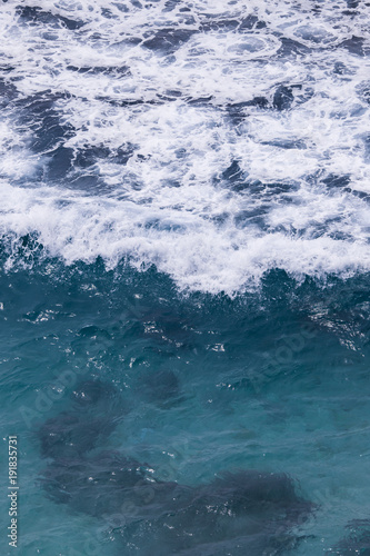 White foam of wave in blue water.