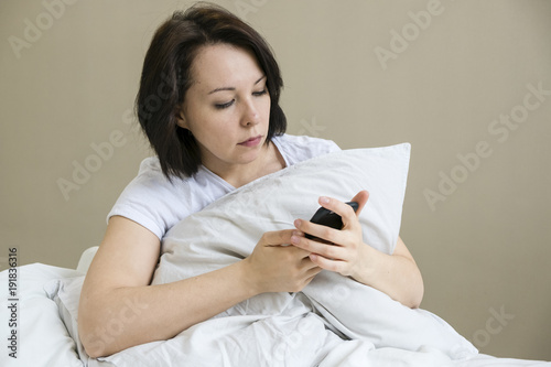 A close up shot of a woman smiling as she interacts with her smartphone. photo