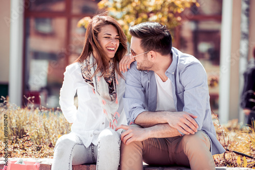 Happy young couple sitting on a bench together.