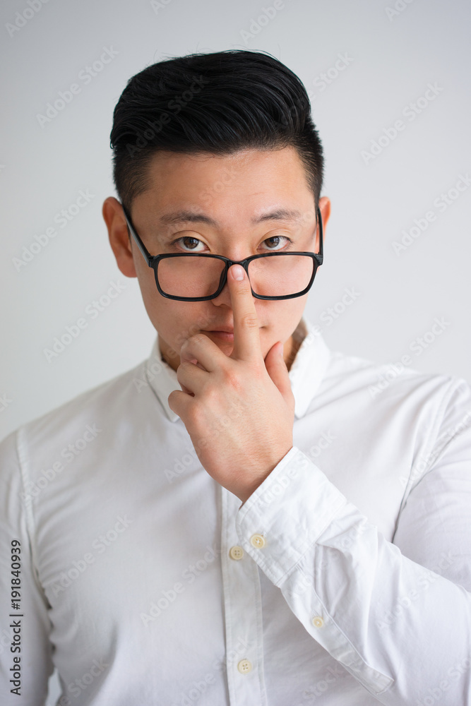 Pensive Asian Student Fixing Glasses with Finger
