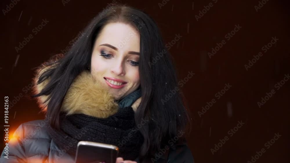 A girl with a smartphone in the winter in a night city with snow A girl with a smartphone in the winter in a night city with snow