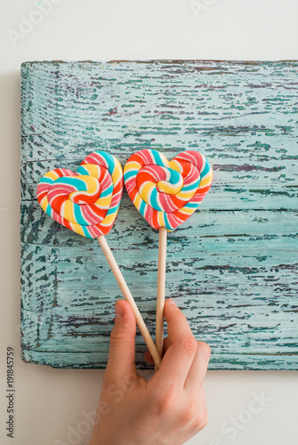 Two colored striped rainbow candy on a stick in the form of a heart. on a blue vintage wooden background. The concept for Valentine's Day. photo