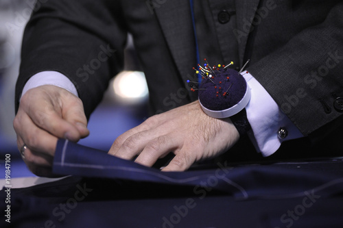 Obraz na plátně Dressmaker’s hands marking fabric cloth on a tailor cutting table