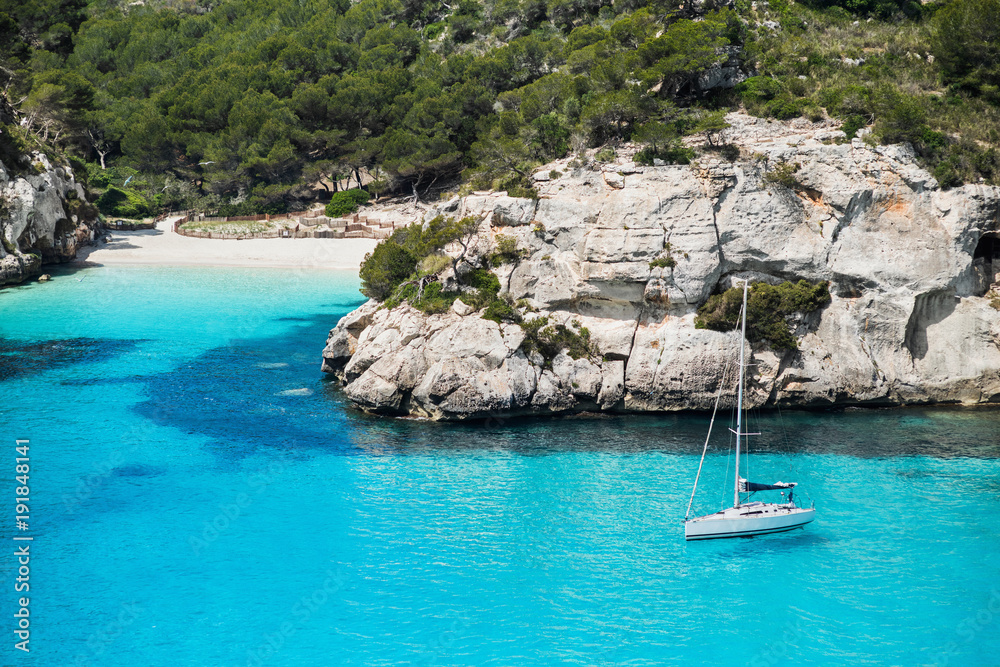 Beautiful bay in Mediterranean sea with sailing boat, Menorca island, Spain. Yachting, travel and active lifestyle concept Beautiful bay in Mediterranean sea with sailing boat, Menorca island, Spain. Yachting, travel and active lifestyle concept