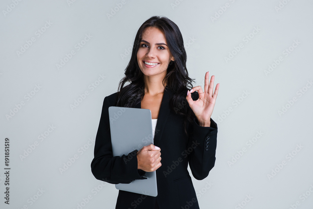 Perfect working day. Beautiful young businesswoman looking at camera and gesturing OK with smile while standing against white background Perfect working day. Beautiful young businesswoman looking at camera and gesturing OK with smile while standing against white background