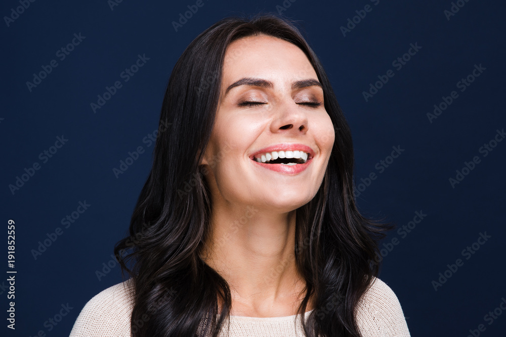 © MARIIA - Pure enjoyment. Portrait of beautiful young woman keeping eyes closed while standing against black background