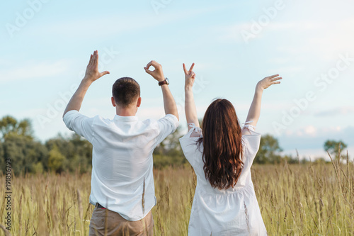 Young couple outdoors showing LOVE sign with their hands. Happy family concept