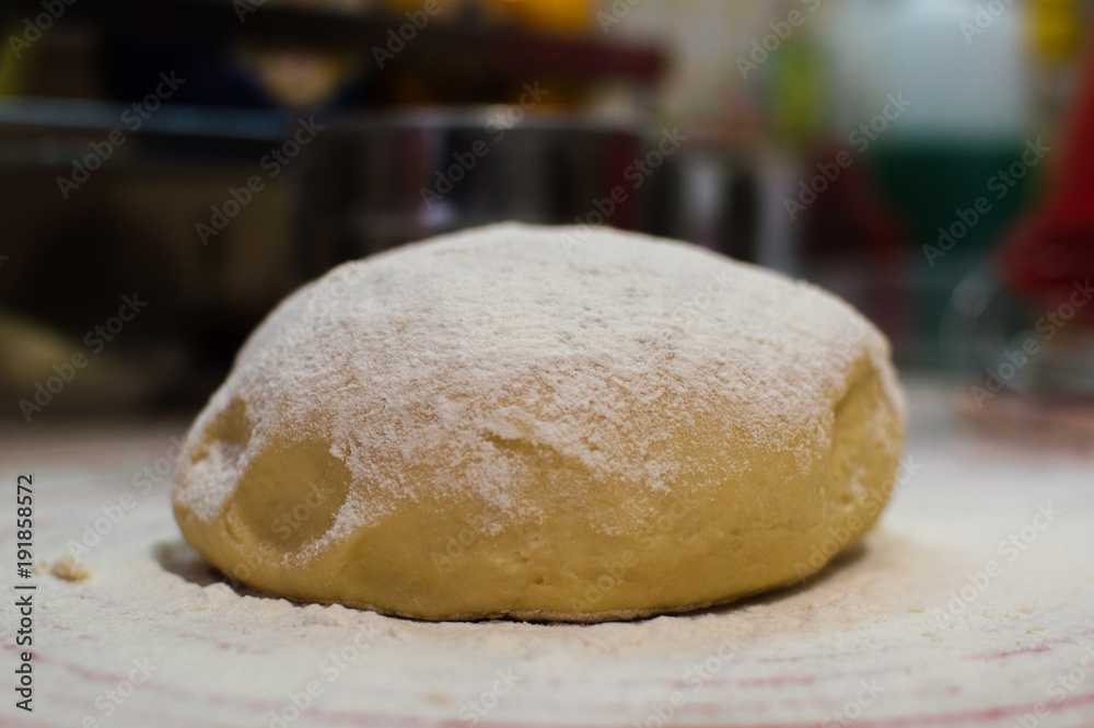 Close-up view of the homemade raw wheat dough ball lying on the modern cooking surface. Dough for pizza, pasta, potstickers.