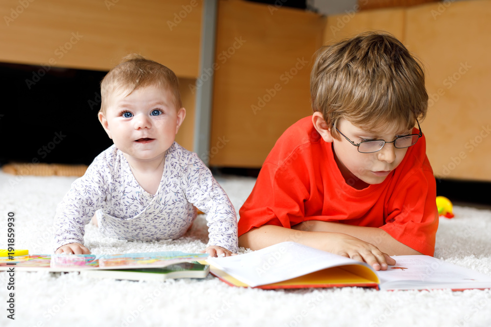 Baby girl and school kid boy reading books at home. Baby girl and school kid boy reading books at home.