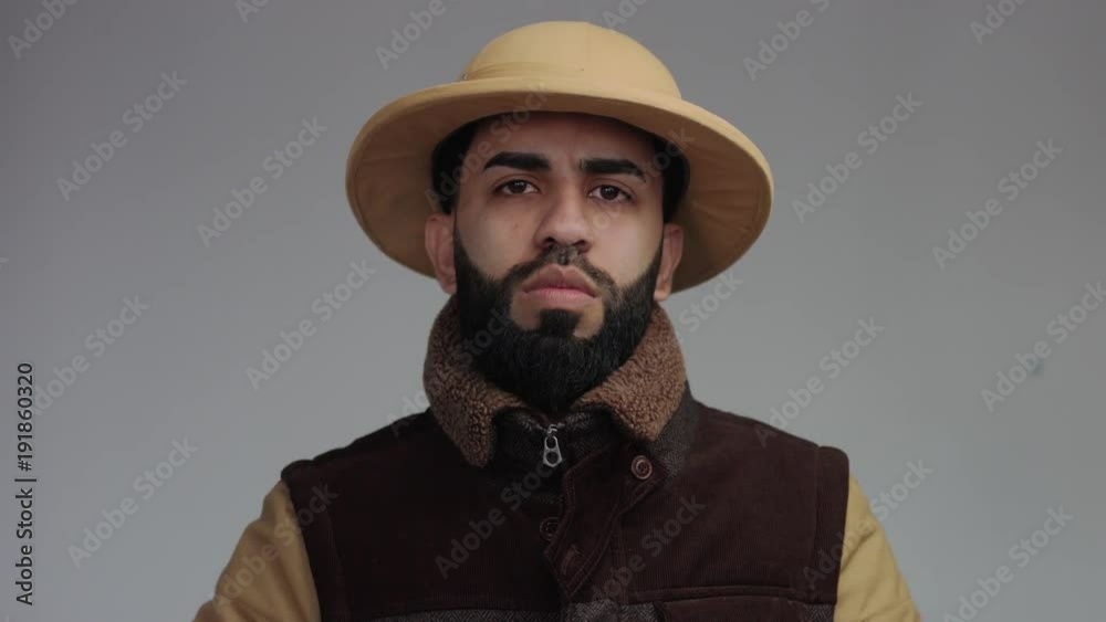 weird man in jacket and african hat in studio. looking serious