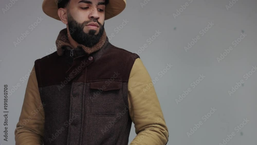 weird man in jacket and african hat in studio. looking serious