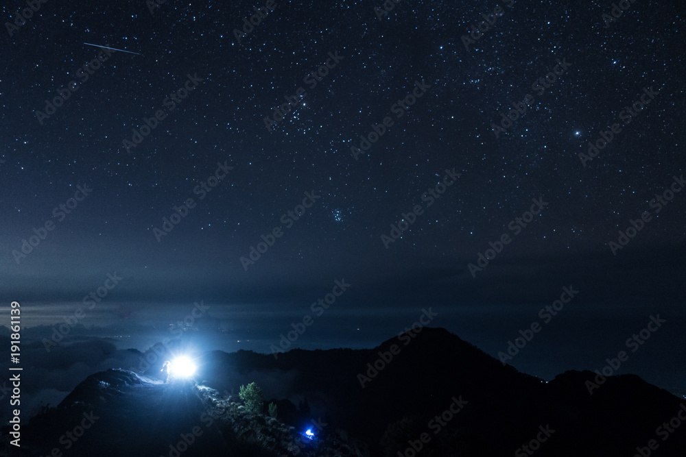 Naklejka premium light from guide in the journey to the summit among the stars above the horizon from Rinjani, Indonesia