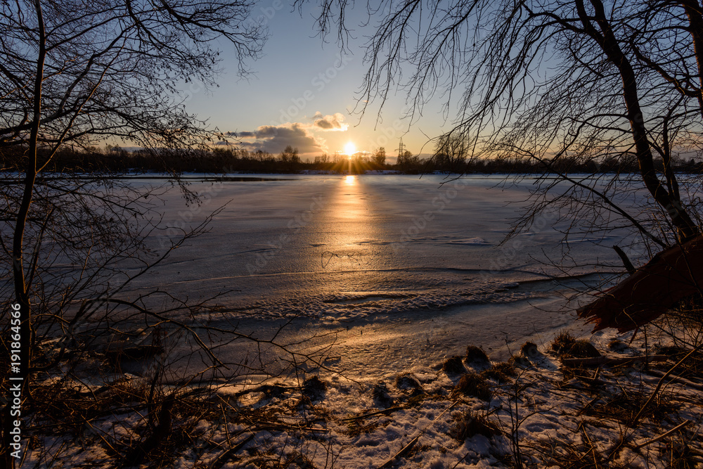 colorful winter sunset with light rays coming through the trees colorful winter sunset with light rays coming through the trees