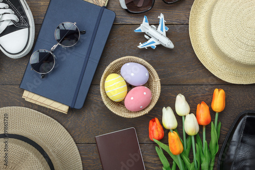 Table top view shot of decoration Happy Easter holiday background concept.Flat lay essential objects plan to travel vacation on modern brown wooden at office desk. Accessory for traveler to trip.