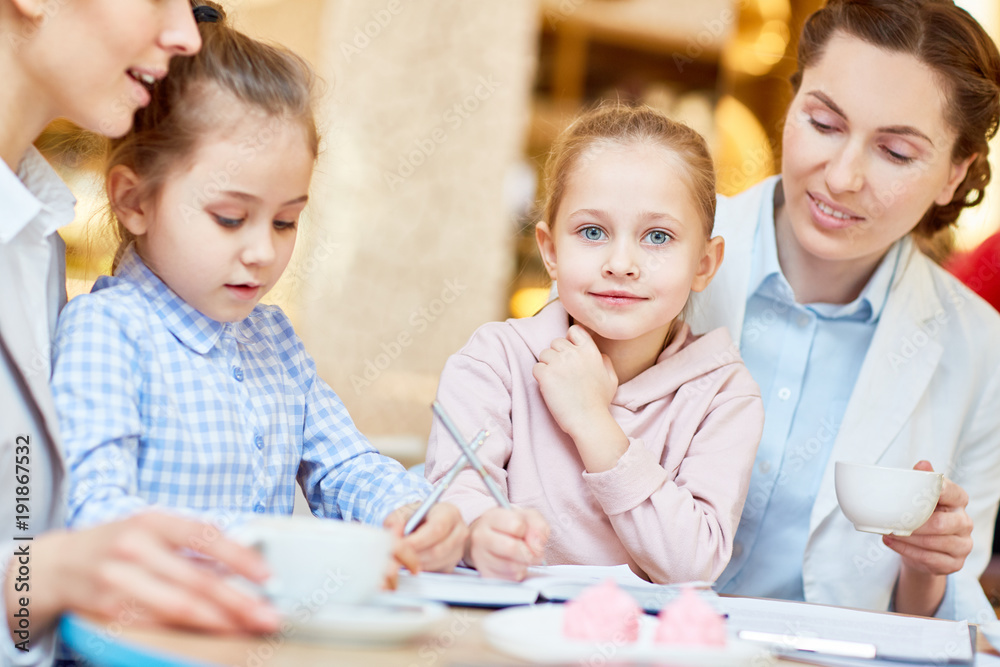 Pretty girl, her friend and mother spending time in cafe while having break