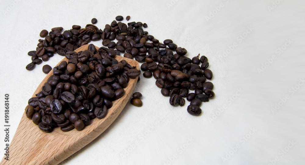 close up of roasted coffee beans on a wood spoon with white background with space for text. close up of roasted coffee beans on a wood spoon with white background with space for text.