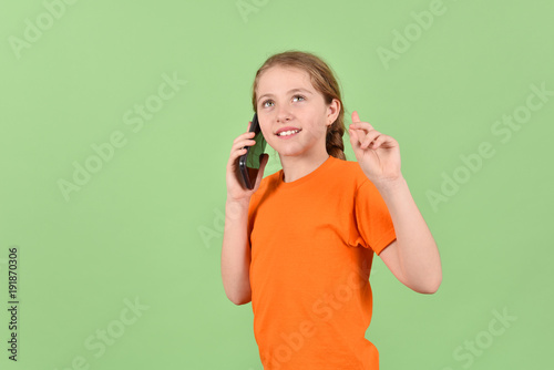 A girl communicates on a mobile phone. A teenage girl on a green background.