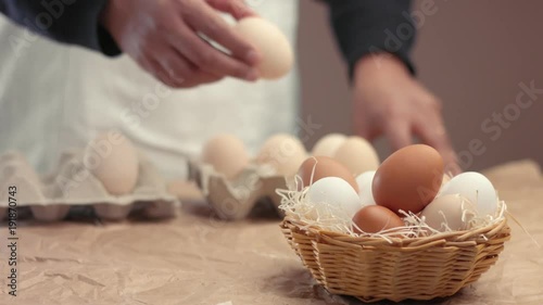 man takes eggs from the basket and put it to the baxoes. Small farmm worker photo