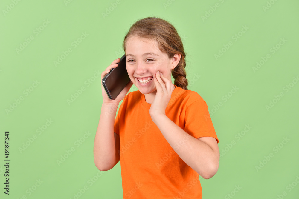 The girl is talking on her cell phone. A girl in an orange T-shirt. The girl is talking on her cell phone. A girl in an orange T-shirt.