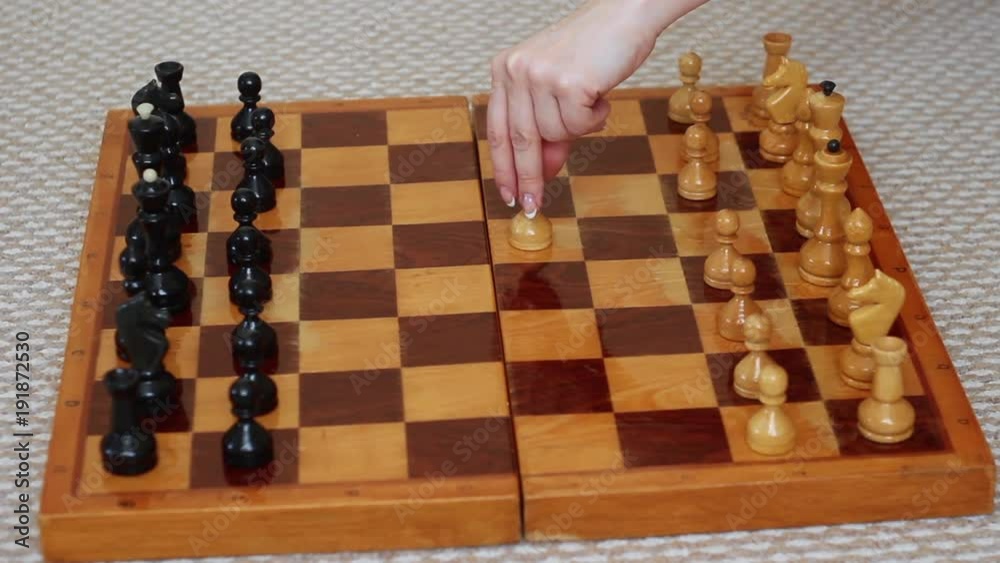 a female hand rearranges the pawn on the chessboard, the beginning of the chess game e2-e4 a female hand rearranges the pawn on the chessboard, the beginning of the chess game e2-e4
