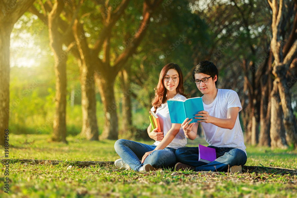 man and woman sitting and reading a book in the park