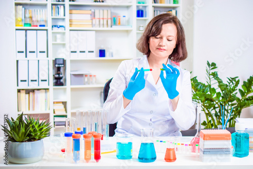 female scientist Injects reagent into the plant in a laboratory. researcher researching in the laboratory. reagent flasks and test tubes with colored chemical reagents on the laboratory work table.