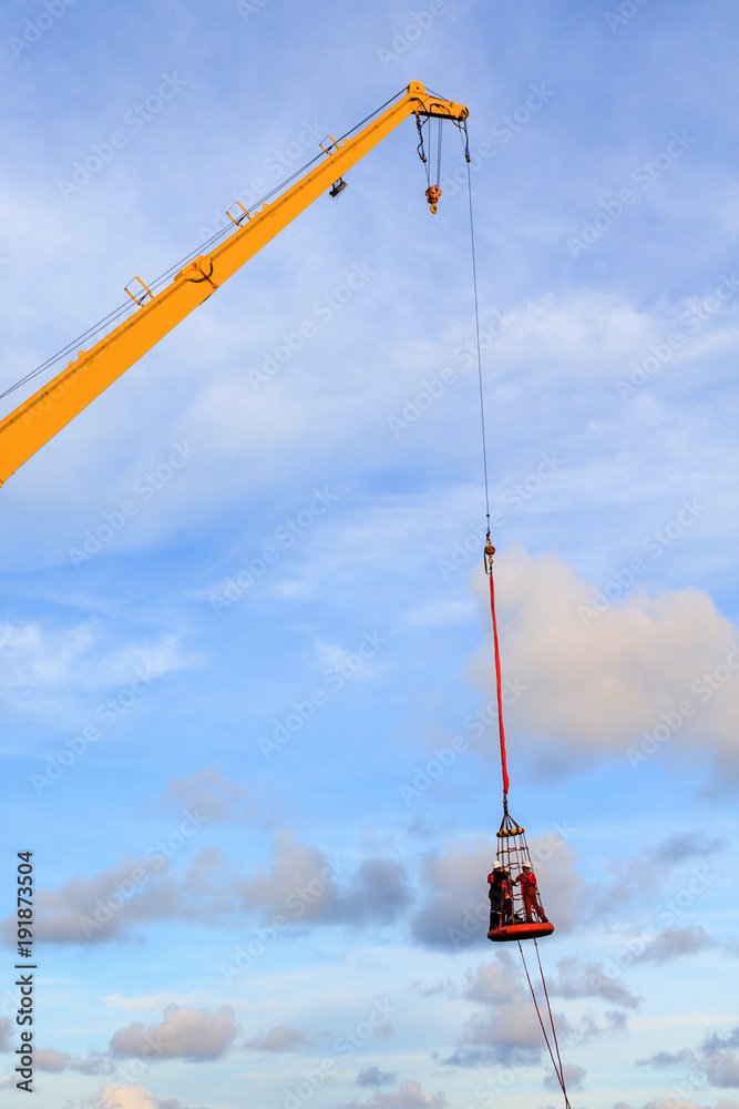 Offshore oil and gas worker using personal basket for transfer by using crane for lift the passenger between supply boat and platform Offshore oil and gas worker using personal basket for transfer by using crane for lift the passenger between supply boat and platform