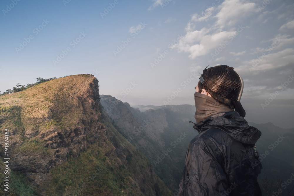 Naklejka premium Handsome man Standing at the back See high peaks, steep brilliant sky spectacular views.