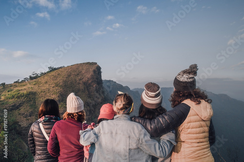 Hiking group at a lovely girl. Standing at the back See high peaks, steep brilliant sky spectacular views.