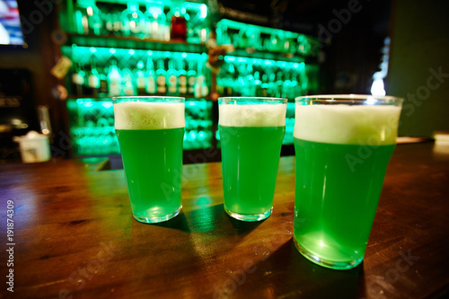 Group of glasses with foaming beer served for friends on bar counter or on wooden table