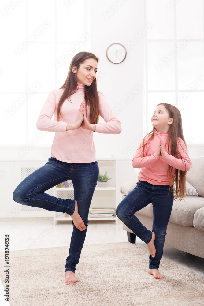 Obraz premium Mother and little daughter doing yoga together at home