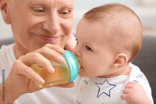 Senior man feeding his litt...