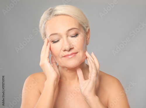 Portrait of beautiful mature woman on grey background. Skin care concept