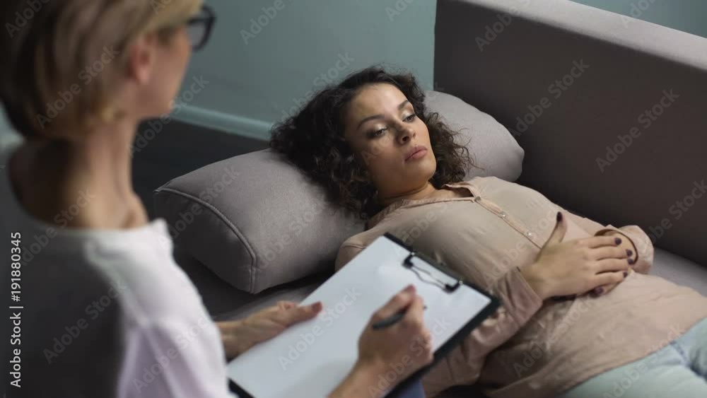 Depressed woman lying on couch and discussing husband betrayal with psychologist Depressed woman lying on couch and discussing husband betrayal with psychologist