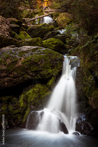 Fototapeta Naklejka Na Ścianę i Meble -  Beautiful fairy mountain waterfall in a fairy forest among rocks at sunset