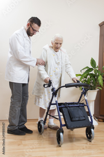2.	Staruszka uczy się chodzić przy pomocy balkonika rehabilitacyjnego  przy asekuracji lekarza.