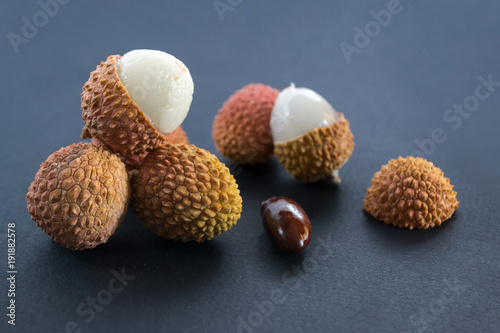 Lychee (Litchi)  with a stone and bright, bumpy skin on dark blue (black) background